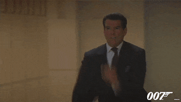 Movie gif. Pierce Brosnan as James Bond in The World Is Not Enough. He's frantically running through a crowd as he yells, "Stop!"