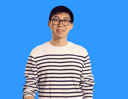 Video gif. A man in a striped shirt and glasses points at us and nods, making a hand heart over his chest.