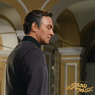 Movie gif. Christopher Plummer as Captain Von Trapp from The Sound of Music turns around to give us a smirk, then laughs briefly and turns away.