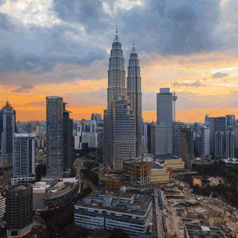 Video gif. A time lapse of the Kuala Lumpur skyline going from day to night. 