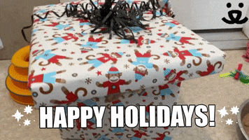 Video gif. We see a Christmas present on the floor, gift-wrapped with pictures of festive monkeys and decorated with thin black ribbons. The top of the box slowly slides off, revealing three curious orange kittens inside. 