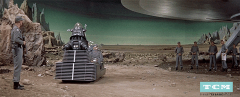 Scene from Forbidden Planet: a robot transporter zips across the screen, carrying three soldiers