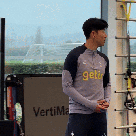 Sports gif. Heung-Min Son and Pape Matar Sarr from Tottenham Hotspur hug each other in the gym.
