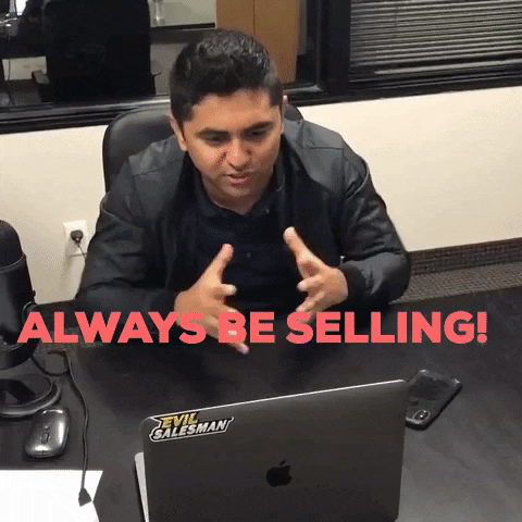 a man sitting at a desk with a laptop that says evil salesman on it