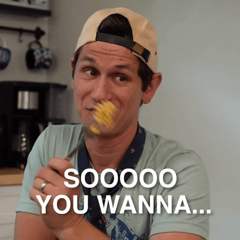 Video gif. Man sits at a kitchen table, waving around a forkful of food as he flirtatiously says, "Soooo you wanna…”
