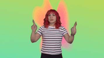 Video gif. Woman points his fingers up and shakes her hips, dancing a little.