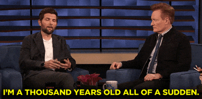 TV gif. Adam Scott is being interviewed by Conan O' Brien on Conan. Adam looks up from his phone and says, "I'm a thousand years old all of a sudden."