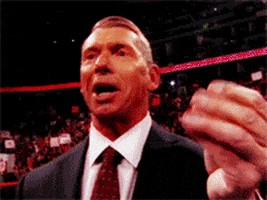 Celebrity gif. Vince McMahon of the WWE basking in rowdy applause, rubs his fingers together to call attention to the lack of money in them, then plunges his hands into a pile of cash, grabbing a stack and sniffing it with virile interest.