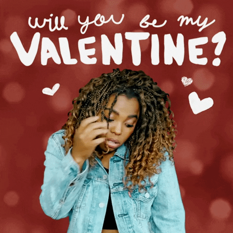 Video gif. A woman looks at us with a shy, awkward, one-corner smile as she runs tucks her curly hair behind her ear. Text, "Will you be my Valentine?"