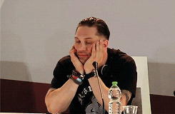 Celebrity gif. Tom Hardy blinks dully from his seat, hands set on his cheeks. Text reads, "I'm hungry."