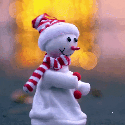 Video gif. A snowman made out of cloth with pom pom buttons and a matching set of a red and white striped hat and scarf spins in a circle on a street. 