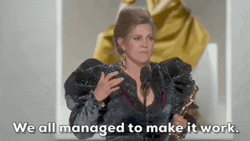 Oscars 2024 gif. Holly Waddington wins Best Costume Design for Poor Things. She wears a shimmering black dress with frilled, bedazzled shoulders and earrings with dangling eyes. She speaks with her hands and seriously says, "We all managed to make it work."