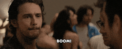 Movie gif. Speaking with a couple of men in This Is the End, James Franco makes a finger gun and says "boom!" which appears as text.
