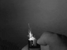 Video gif. Slow motion black and white of a lighter sparking.