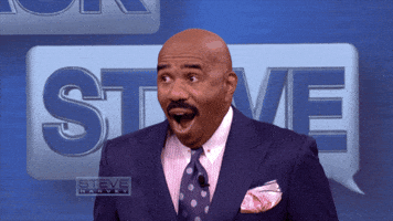 TV gif. Steve Harvey on his show looks shocked and then smiles really awkwardly in reaction to something. 