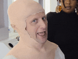 Celebrity gif. Tim Robinson from I Think You Should Leave with Tim Robinson wears a rubber head prosthetic that is ill-fitted on his head. He sticks his tongue out and holds his hand up in the rock and roll symbol.