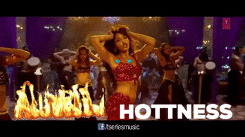 Celebrity gif. Neha Kakkar seductively dances on stage, surrounded by belly dancers. A blazing fire, a face with eyeballs that pop out, and the word “hotness” are transposed over the video.