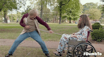 Movie gif. Jim Carrey as Llyod and Jeff Daniels as Harry in Dumb and Dumber. Llyod is in a wheelchair with a catheter on and Harry pulls Lloyd out of the wheelchair by yanking the catheter and Lloyds hips rise high before his body flies off.