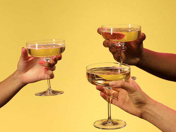 Video gif. Three people's hands reach into the frame to clink their wine glasses together.