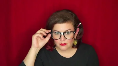 GIF of Christine on a red background peering down her glasses at you