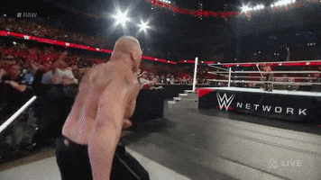Sports gif. Brock Lesnar from WWE approaches the ring and takes off in a sprint, launching over the side and trying to tackle his opponent.
