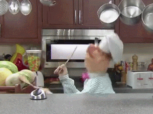 A GIF of the Swedish Chef from The Muppets dancing and banging spoons against melons in his kitchen.