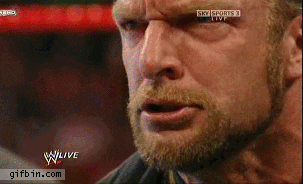 TV gif. Close up on a Wrestler’s face as he trembles with anger. His face is tense and tight as he stares down his opponent.