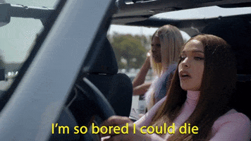 Music video gif. Princess Nokia in the video for Simple Times by Kacey Musgraves sits in the driver's seat of a car and holds onto the steering wheel as she says, "I'm so bored I could die."
