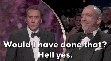 Oscars 2024 GIF. Split screen of Nicolas Cage speaking about Paul Giamatti, who watches from the audience. Cage speaks matter of factly as he says, "Would I have done that? Hell yes." Giametti raises his eyebrows and grins with a closed lipped smile in amusement.