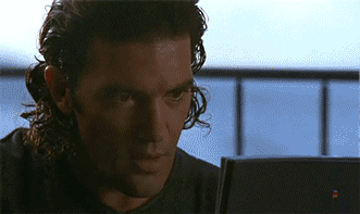 Meme gif. Antonio Banderas as Miguel Bain in Assassins looking at a laptop with astonishment, leans back in his chair, exhaling in delight, touching a loose fist to his lips in satisfaction.