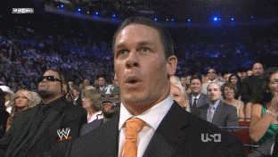 Sports gif. John Cena at a W fight with his eyebrows raised exaggeratedly and he makes a shocked fish face. Something's happened that has surprised and amused him.