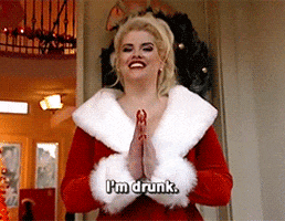 Celebrity gif. Anna Nicole Smith wearing a Santa Claus coat leans towards us with her palms together, shaking her head around a bit as she laughs widely. Text reads, “I’m drunk.”