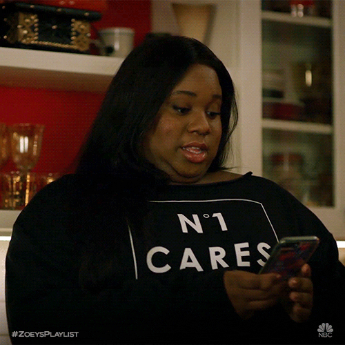 TV gif. Alex Newell as Mo in Zoey's Extraordinary Playlist looks at her phone and flares her eyes for a moment as she types or scrolls.