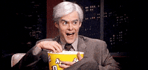SNL gif. Bill Hader as Keith Morrison from DateLine looking eerily excited, nodding his head and eating from a big tub of popcorn.
