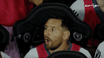 Sports gif. Lionel Messi and other members of Inter Miami CF all jump up from their seats at once, pumping their fists in celebration and screaming loudly.