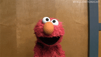 Tonight Show gif. Elmo turns to look at us with his mouth open wide in shock or confusion. 