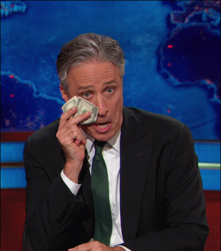 Daily Show gif. Pretending to cry, Jon Stewart wipes his tears with a hundred-dollar bill.