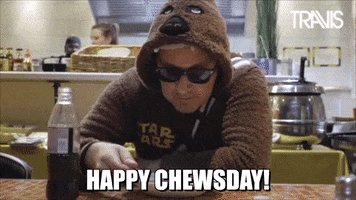Celebrity gif. Andy Dunlop wears sunglasses and a Chewbacca hoodie and sips from a spoon as he hunches over a bowl of food. Text, "Happy Chewsday."