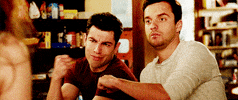 TV gif. Jake Johnson as Nick in New Girl stares out and fist-bumps Max Greenfield as Schmidt, who makes an explosion gesture with his hand.