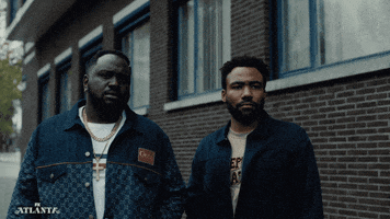 TV gif. Donald Glover as Earnest and Brian Tyree Henry as Alfred in Atlanta. The men are staring at someone and Earnest gives them a confused wave as Alfred sees him wave and stares at him.