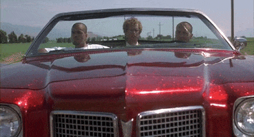 Movie gif. Jon Heder as Napoleon in Napoleon Dynamite. He sits in a red glittery convertible lowrider and is taking a road trip with two men, looking incredibly out of place.