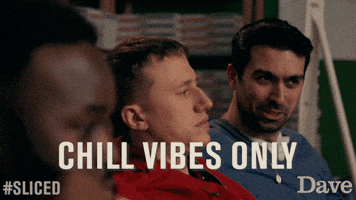 TV gif. David Mumeni as Mario from Sliced flashes a peace sign and turns to his friends with a corny smile mouthing "chill vibes only". His are friends sitting in a row next to him and appear in the foreground. Text, "chill vibes only."