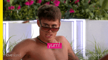 Reality TV gif. In a clip from Love Island, a young man with arm tattoos gives us a saucy roll of his neck as he says: Text, "Yum!"