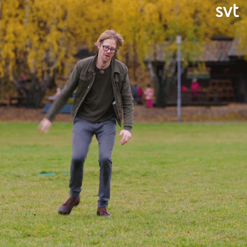 TV gif. Anders Johansson, a Swedish comedian, is standing in a park and he tries to do a cartwheel. He fails terribly and falls onto his side while rolling over and smiling.