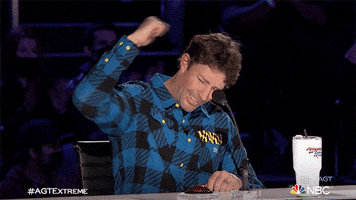 Reality TV gif. Travis Pastrana as a judge on America's Got Talent shakes his fist excitedly to show how pumped he is.