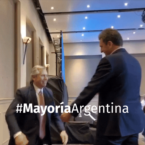 Political gif. Alberto Fernández hugs another politician on stage with the caption, “#MayoriaArgentina.”