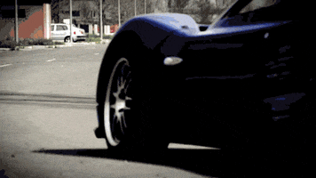 Video gif. A Pagani Zonda, a luxury racecar, is driving on a curve and it performs a powerslide, drifting as it speeds away. 