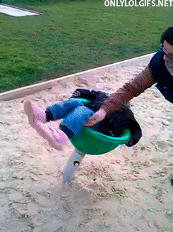 Video gif. A child is lying prone on a park spinner and is being spun very, very rapidly. She flys off the spinner and lands on the sand next to it because the velocity is too much to bear. 