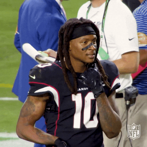 NFL gif. Arizona Cardinals wide receiver DeAndre Hopkins stands on the football field holding the collar of his jersey. "Damn," he says, disappointed. Text: "Damn."