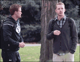 Video gif. Two college students go to high five, but then they decide to switch it to a fist bump. They then try to high five, but still can't decide on if they wanna do a fist bump. One of them goes in for a hug, but they both hesitate awkwardly. They finally end up hugging. 